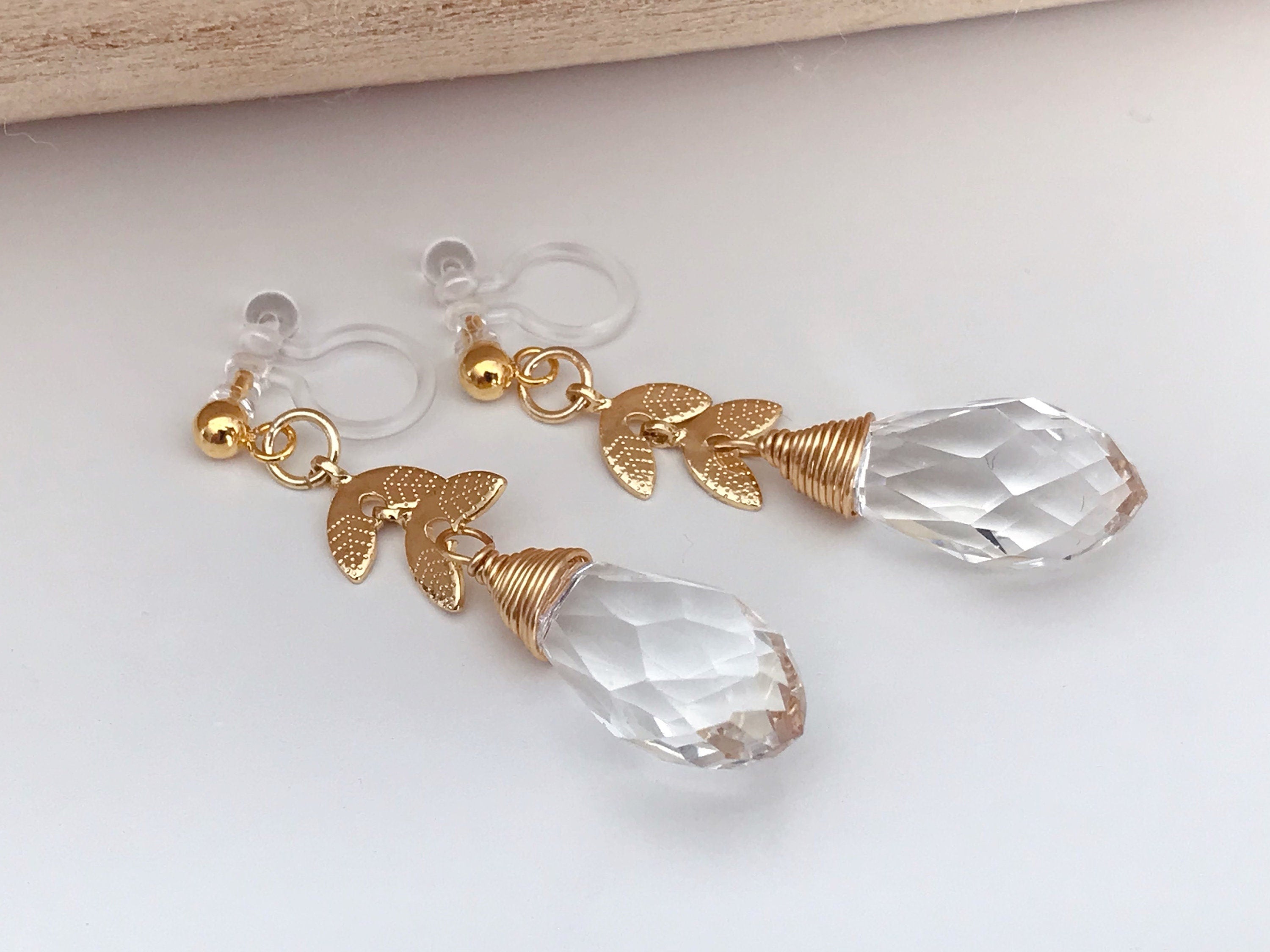Gold leaf chain dangling ear clips with transparent faceted pearl in the shape of a drop of water Comfortable invisible clips.