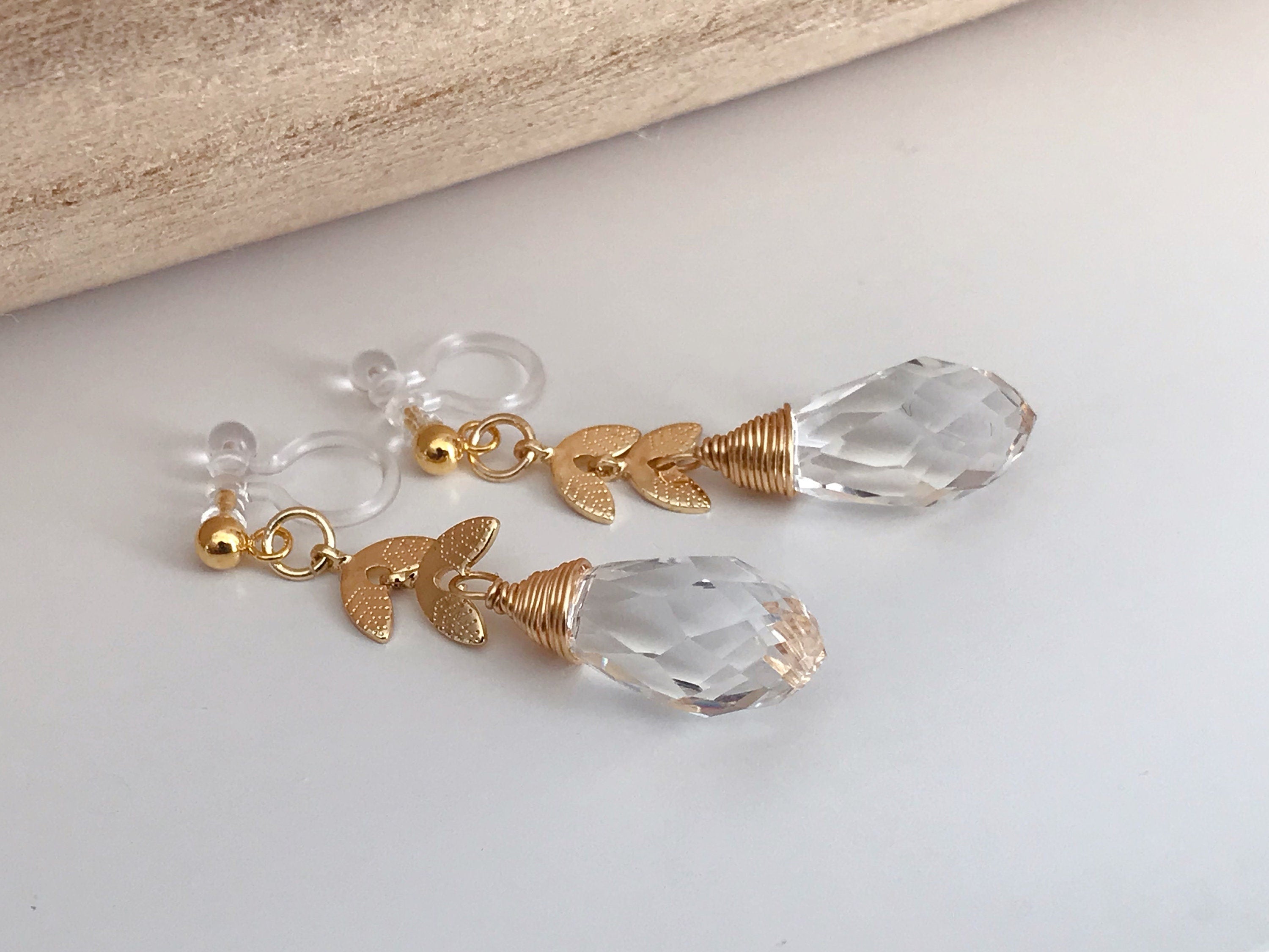 Gold leaf chain dangling ear clips with transparent faceted pearl in the shape of a drop of water Comfortable invisible clips.