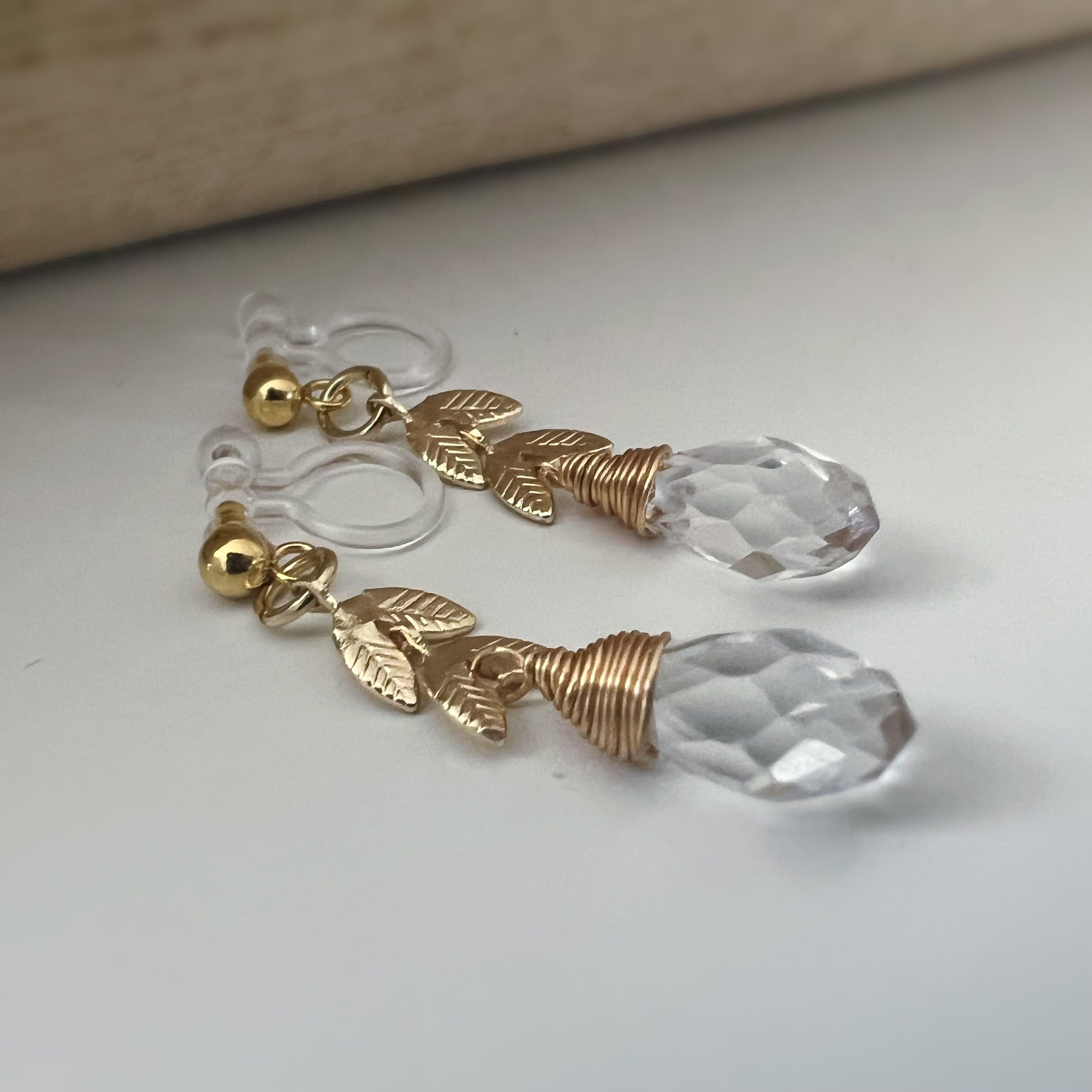 Gold leaf chain dangling ear clips with transparent faceted pearl in the shape of a drop of water Comfortable invisible clips.