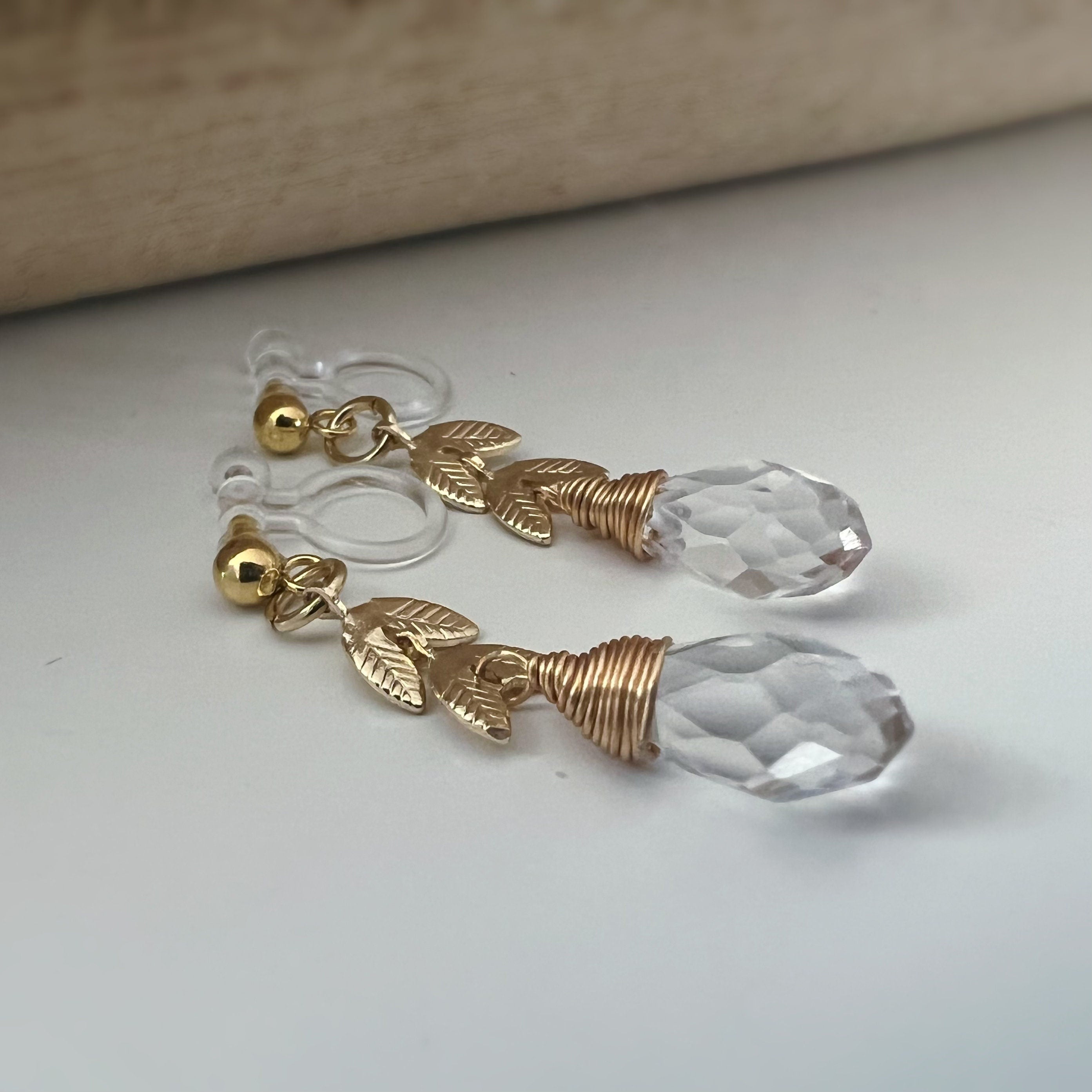 Gold leaf chain dangling ear clips with transparent faceted pearl in the shape of a drop of water Comfortable invisible clips.