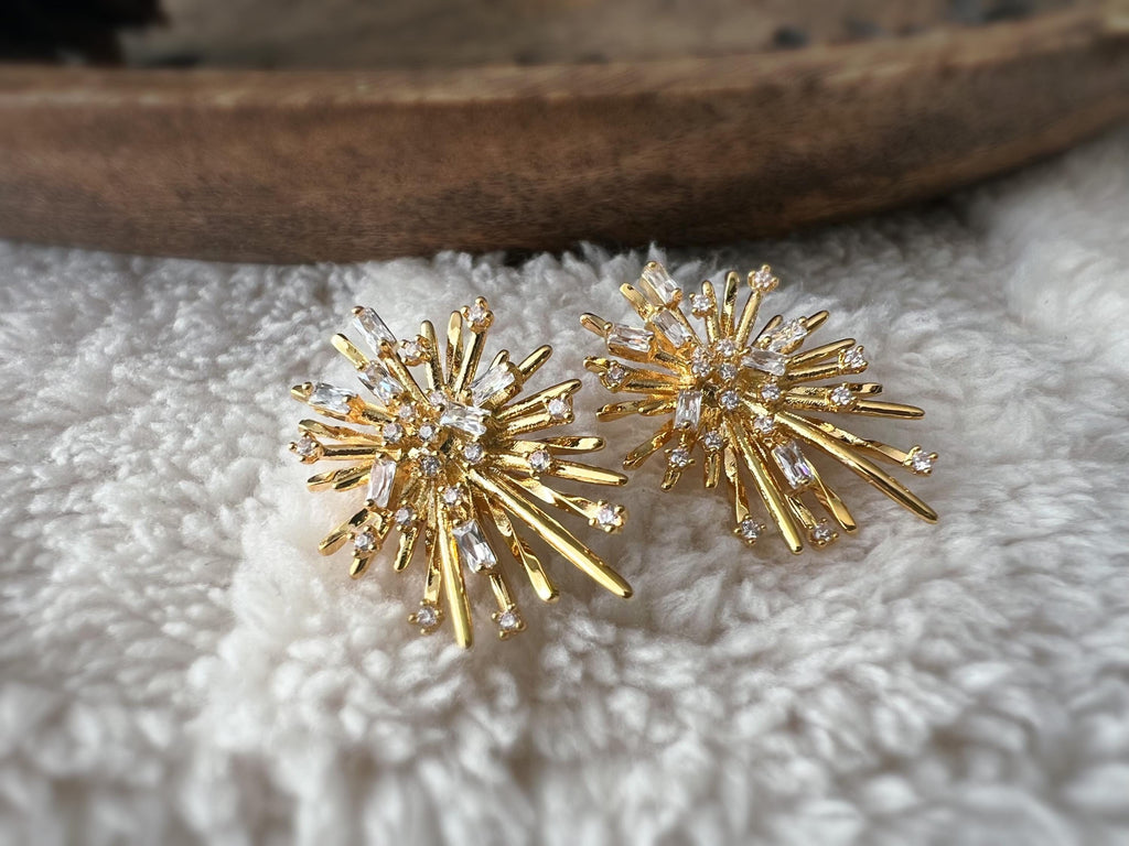 Clips d'oreilles dorés en forme de rayons lumineux, sertis de cristaux étincelants. Une touche glamour idéale pour sublimer vos tenues.