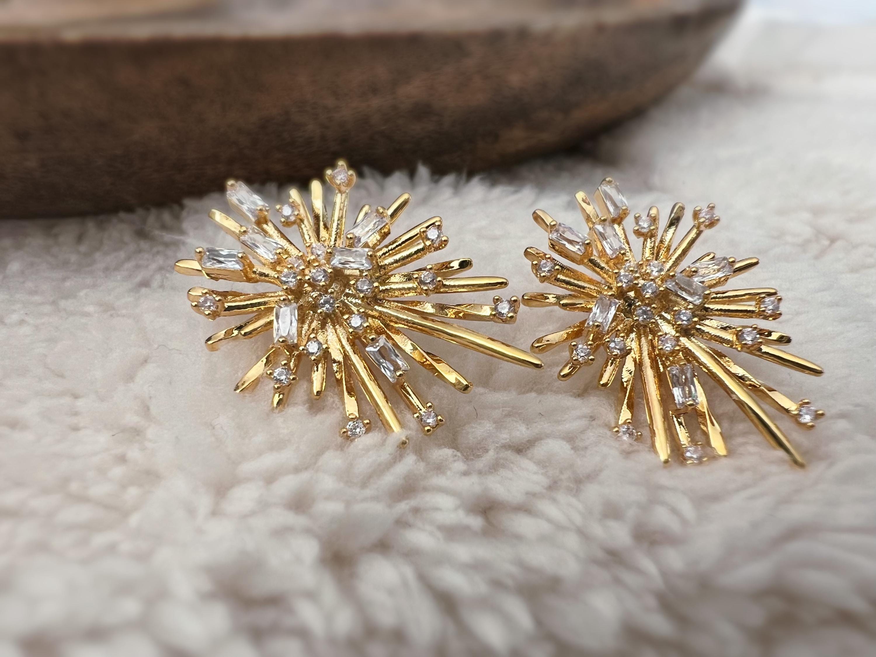 Clips d'oreilles dorés en forme de rayons lumineux, sertis de cristaux étincelants. Une touche glamour idéale pour sublimer vos tenues.