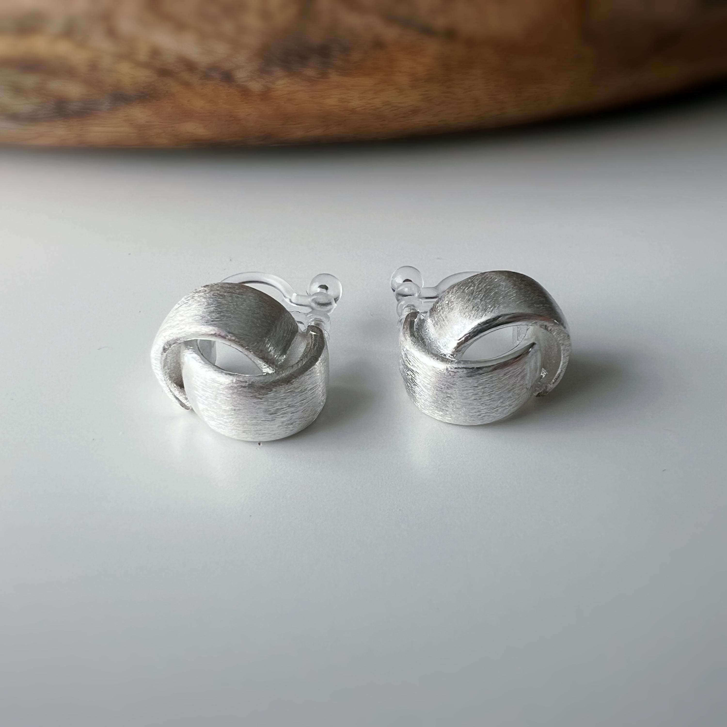 Boucles d'oreilles clip argent brossé au design torsadé élégant. Légères confortables grâce à leur clip transparent, oreilles non percées.