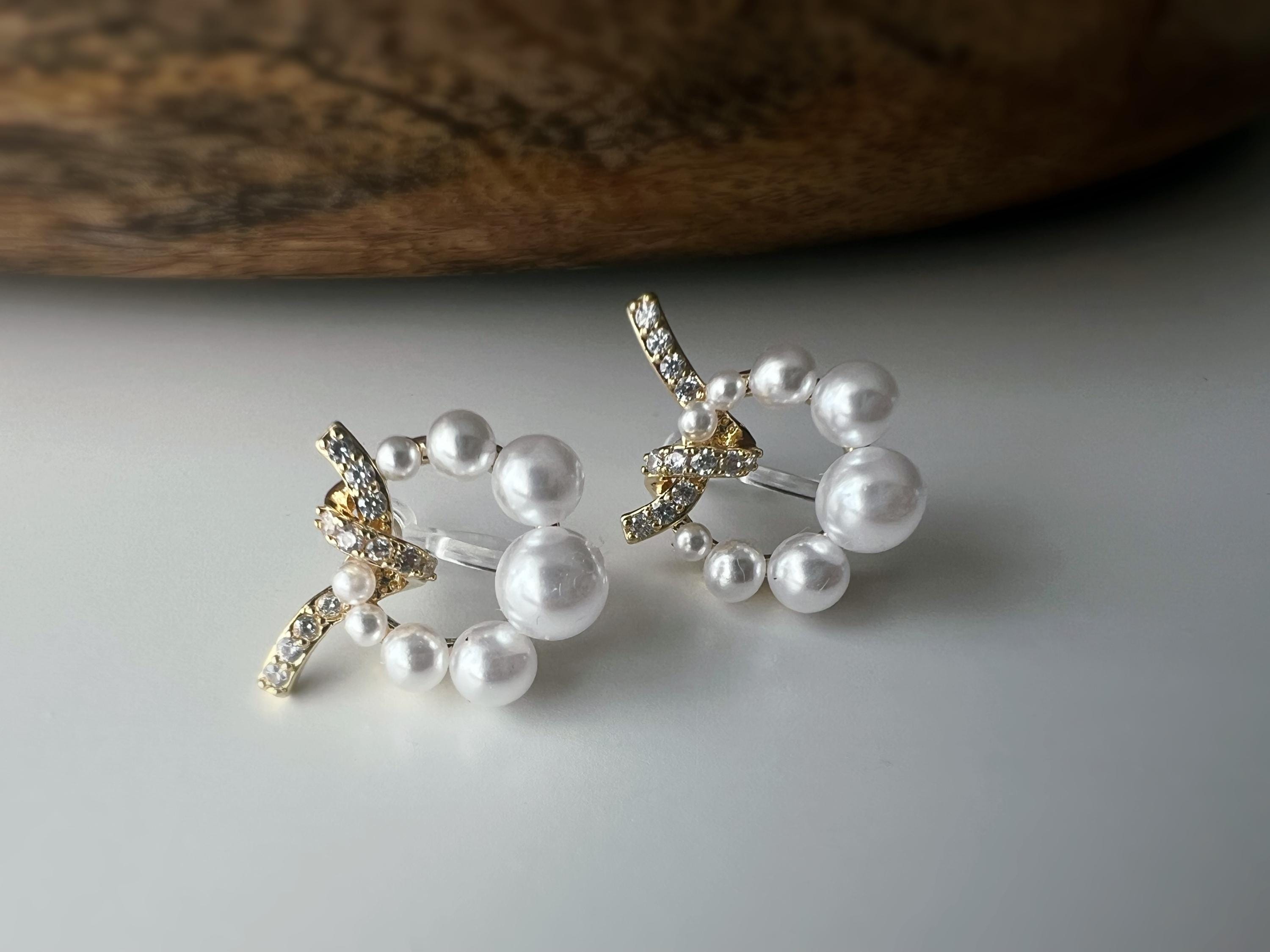 Boucles d’oreilles clip forme de couronne ornées perles blanches, strass scintillants. Finition dorée raffinée pour une touche sophistiquée.