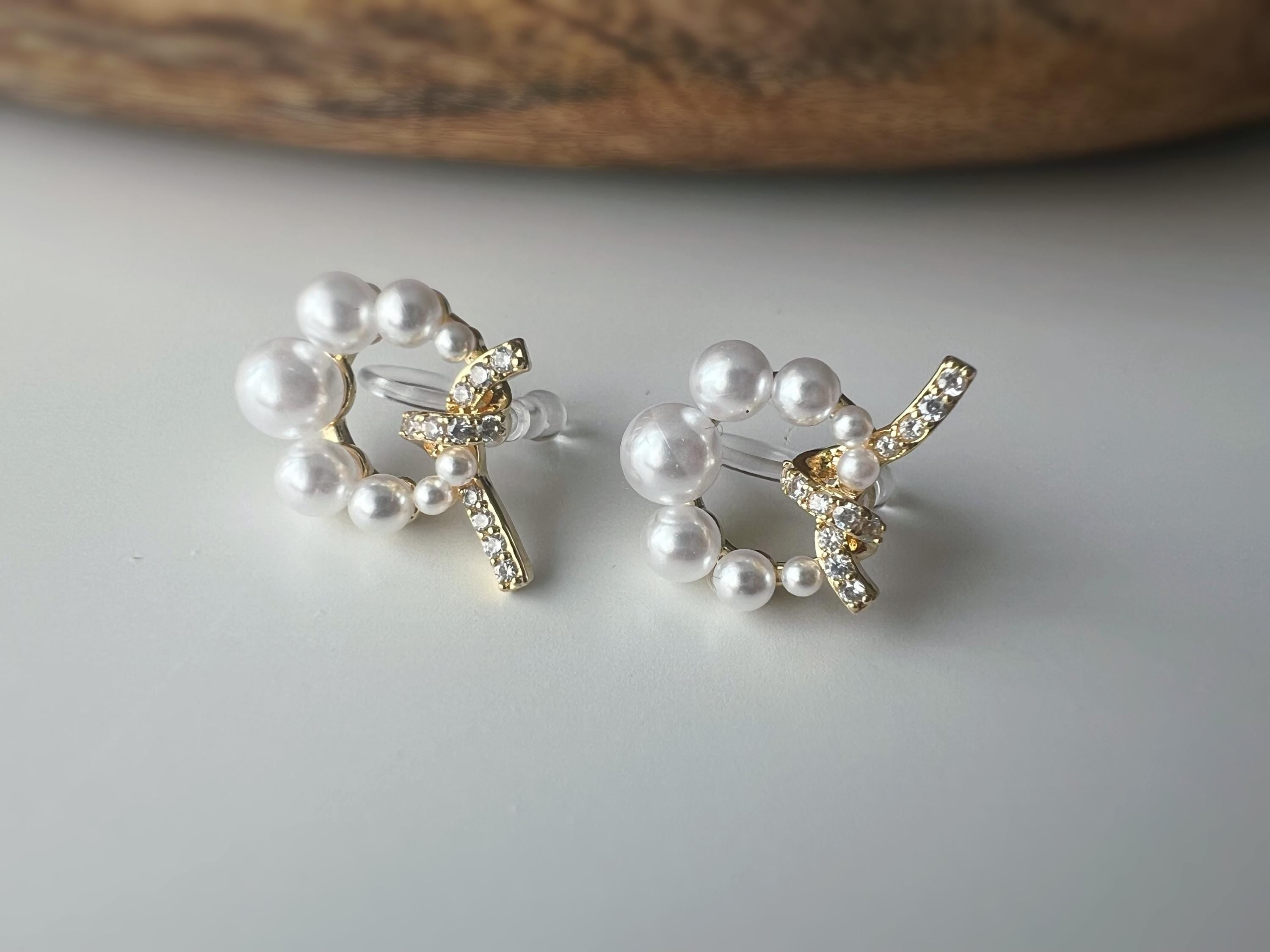 Boucles d’oreilles clip forme de couronne ornées perles blanches, strass scintillants. Finition dorée raffinée pour une touche sophistiquée.