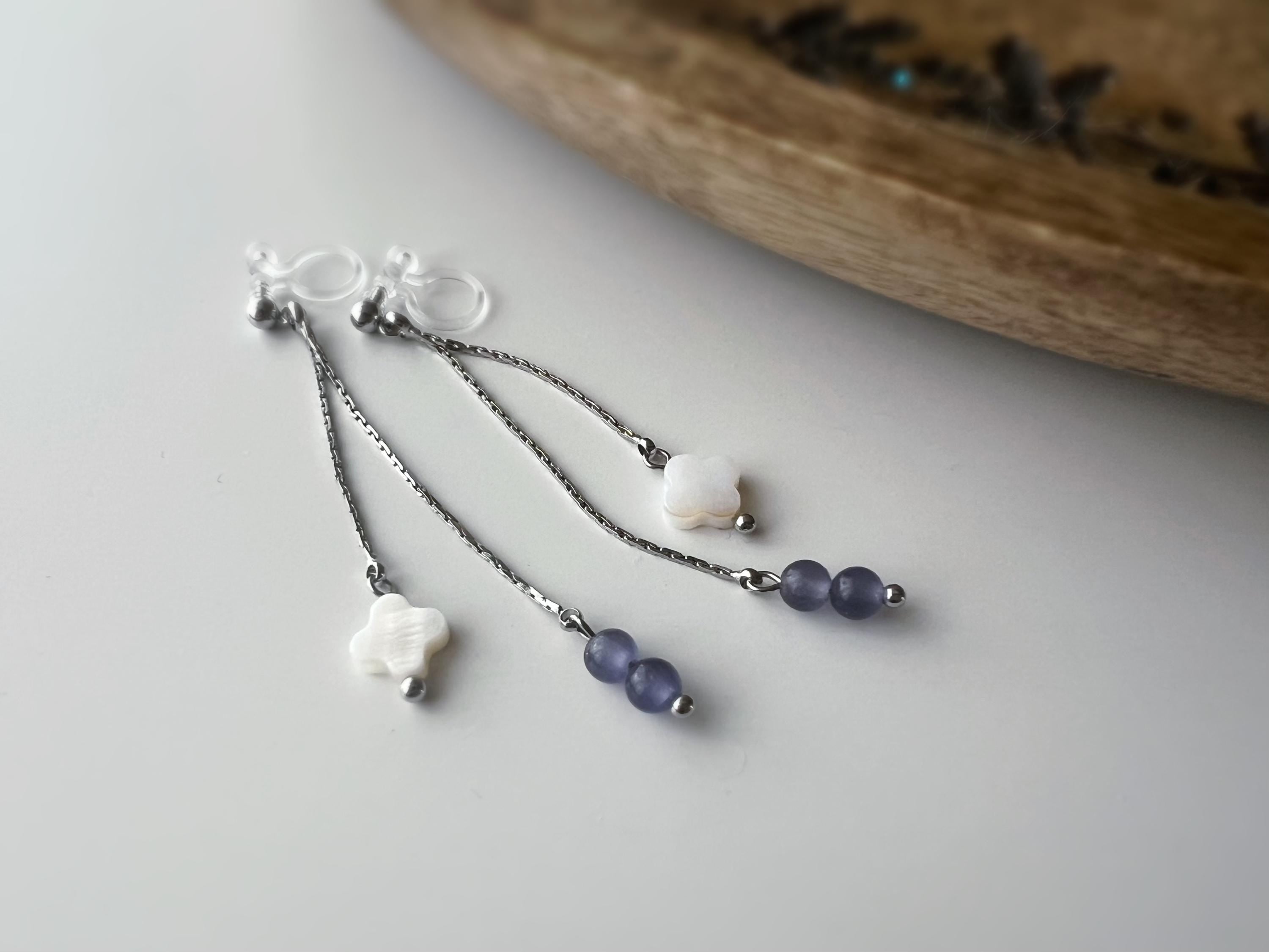 Boucles d'oreilles clip élégantes Chaîne argentée Perles violettes Fleur blanche en nacre Légères raffinées parfait pour style délicat chic.