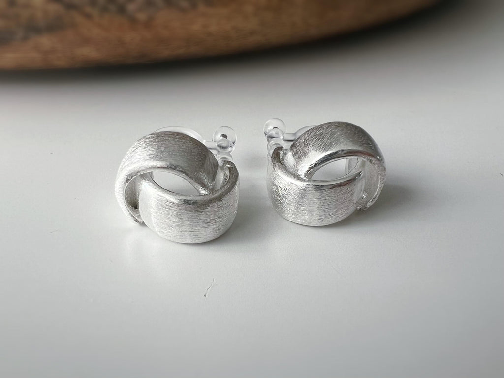 Boucles d'oreilles clip argent brossé au design torsadé élégant. Légères confortables grâce à leur clip transparent, oreilles non percées.