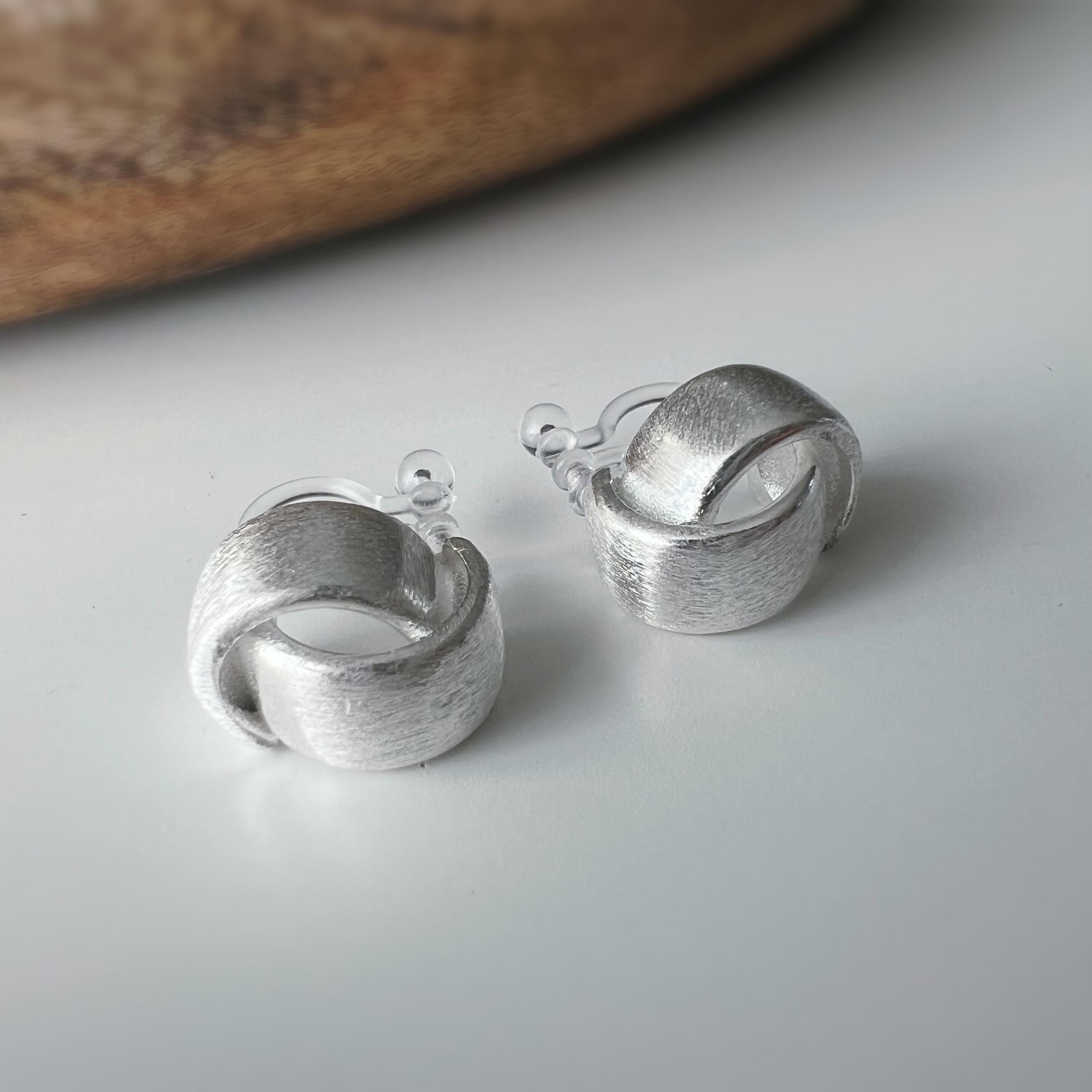 Boucles d'oreilles clip argent brossé au design torsadé élégant. Légères confortables grâce à leur clip transparent, oreilles non percées.