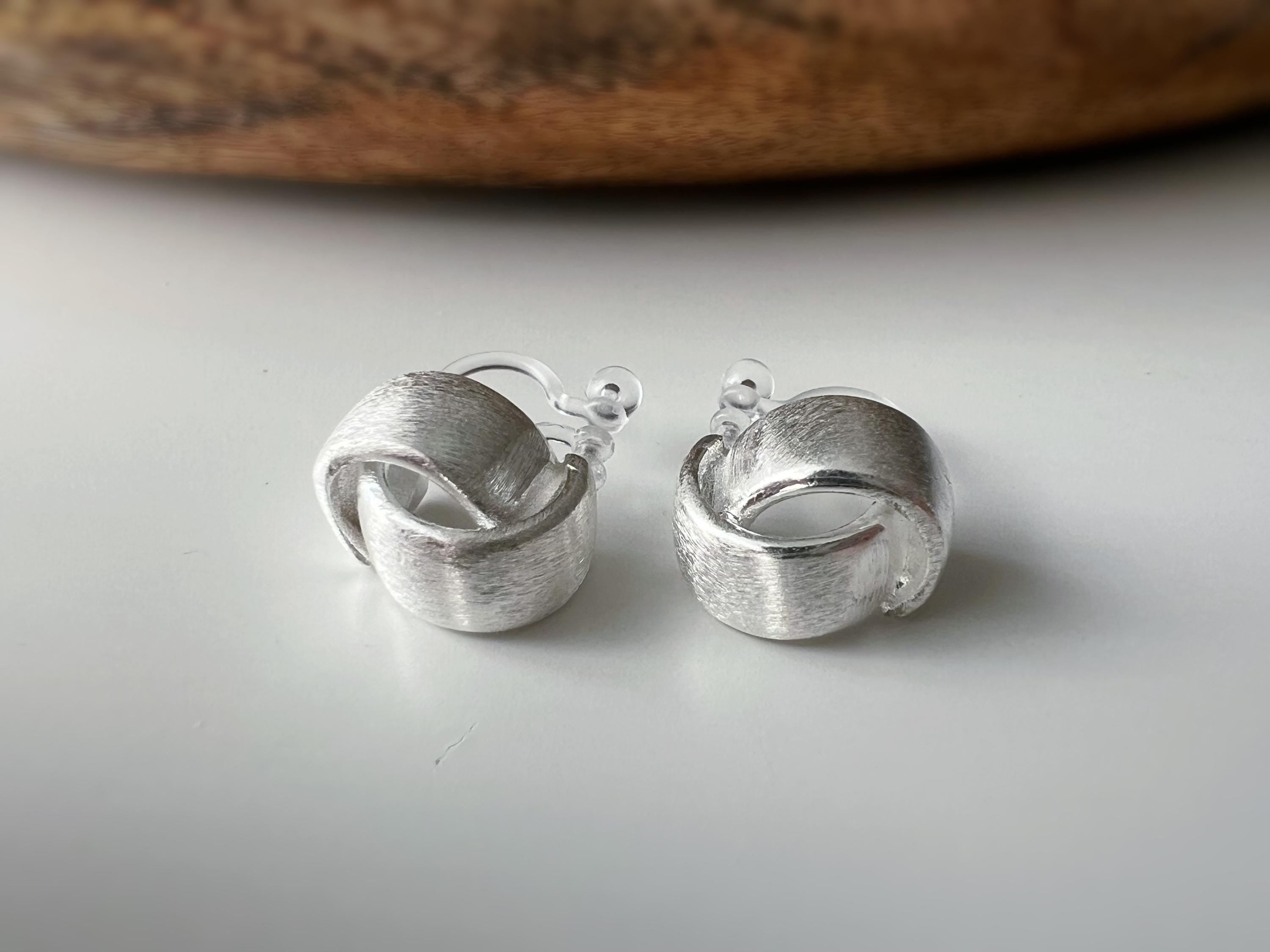 Boucles d'oreilles clip argent brossé au design torsadé élégant. Légères confortables grâce à leur clip transparent, oreilles non percées.