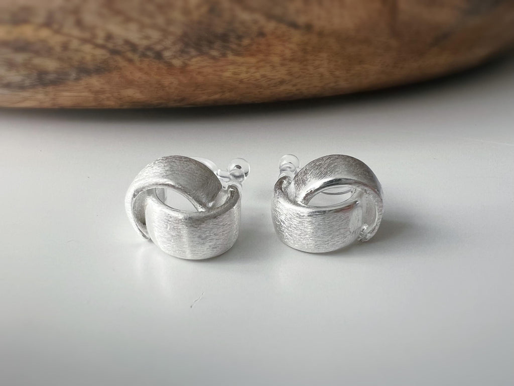 Boucles d'oreilles clip argent brossé au design torsadé élégant. Légères confortables grâce à leur clip transparent, oreilles non percées.