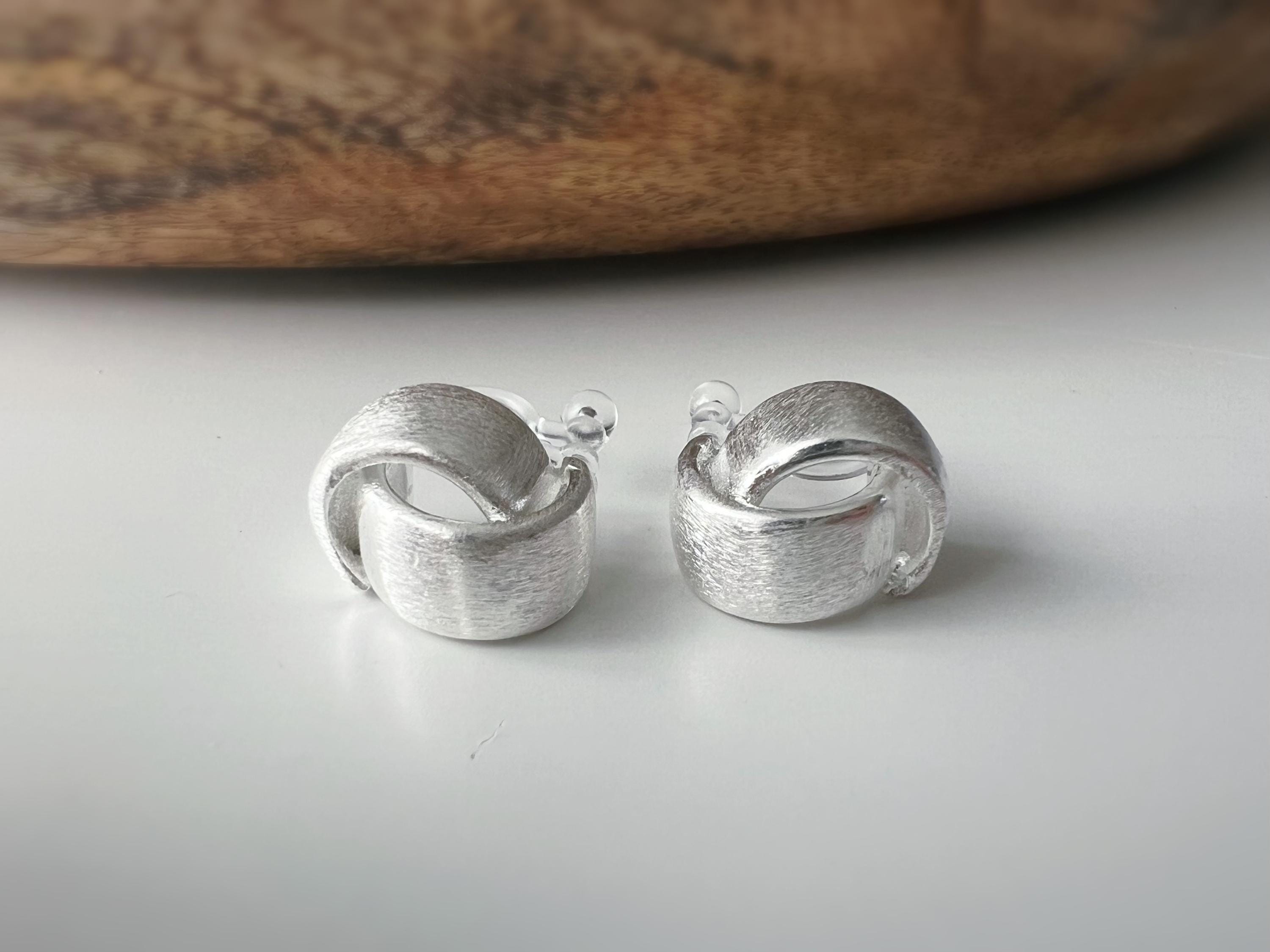 Boucles d'oreilles clip argent brossé au design torsadé élégant. Légères confortables grâce à leur clip transparent, oreilles non percées.