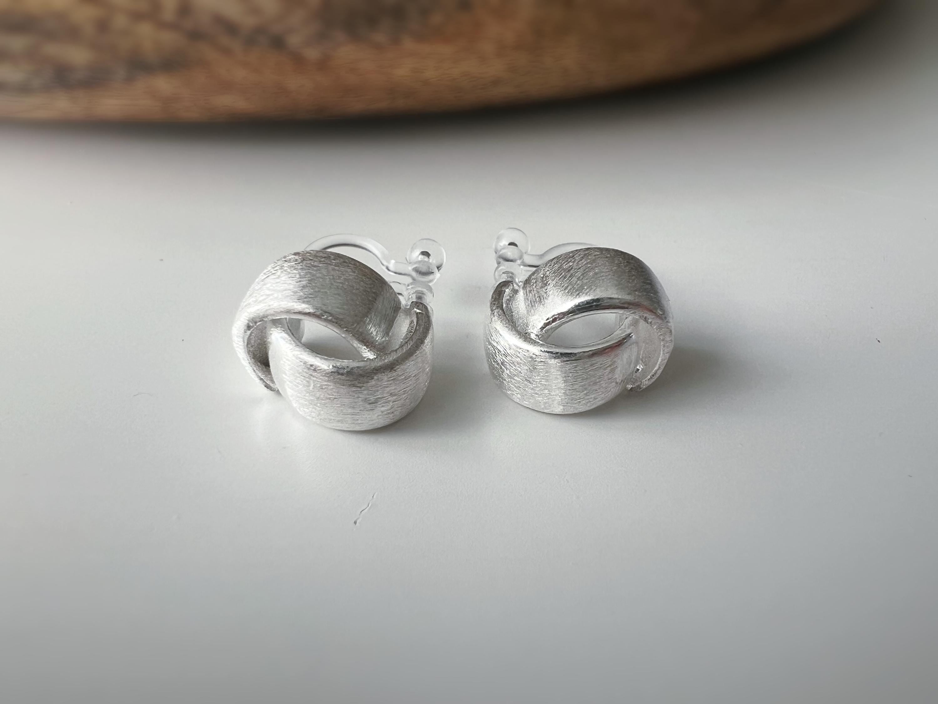 Boucles d'oreilles clip argent brossé au design torsadé élégant. Légères confortables grâce à leur clip transparent, oreilles non percées.