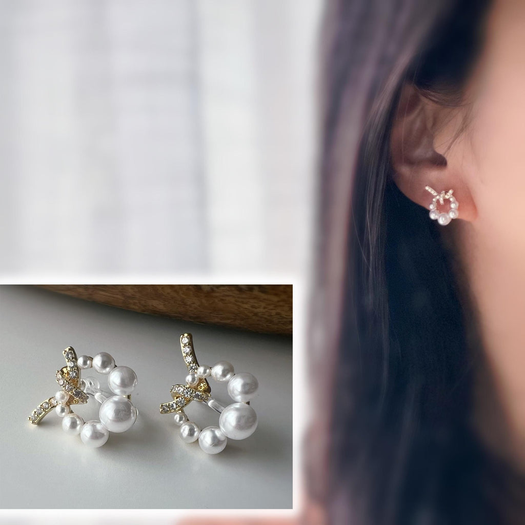 Boucles d’oreilles clip forme de couronne ornées perles blanches, strass scintillants. Finition dorée raffinée pour une touche sophistiquée.
