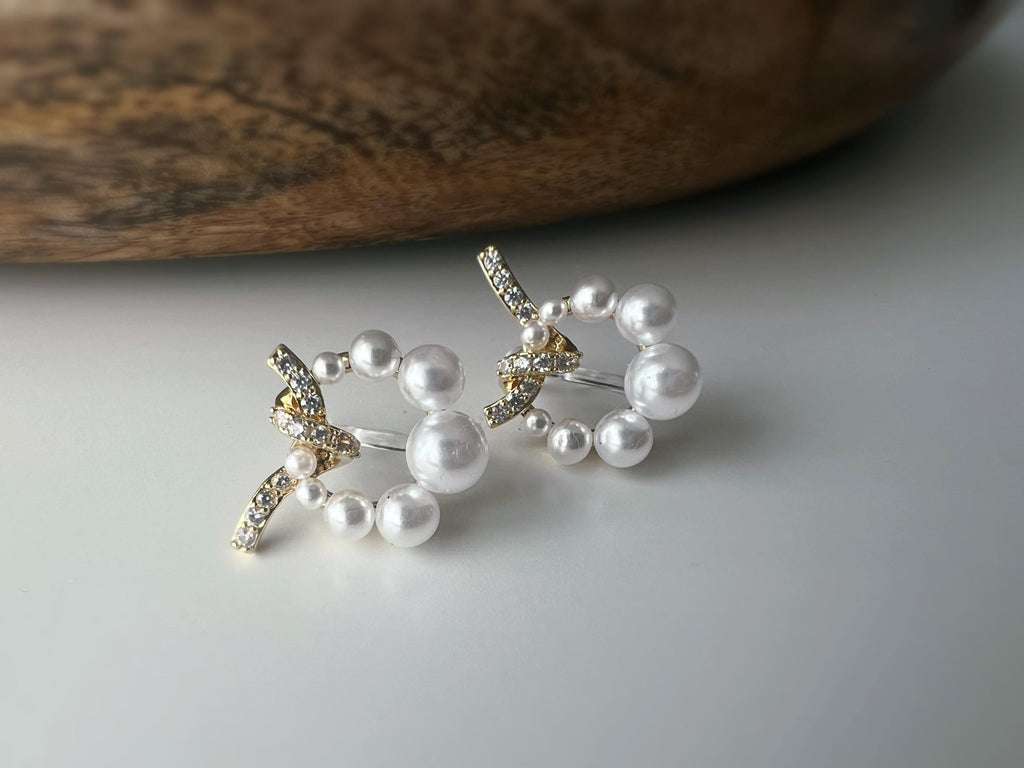 Boucles d’oreilles clip forme de couronne ornées perles blanches, strass scintillants. Finition dorée raffinée pour une touche sophistiquée.