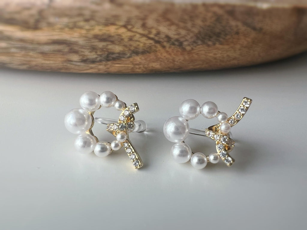 Boucles d’oreilles clip forme de couronne ornées perles blanches, strass scintillants. Finition dorée raffinée pour une touche sophistiquée.
