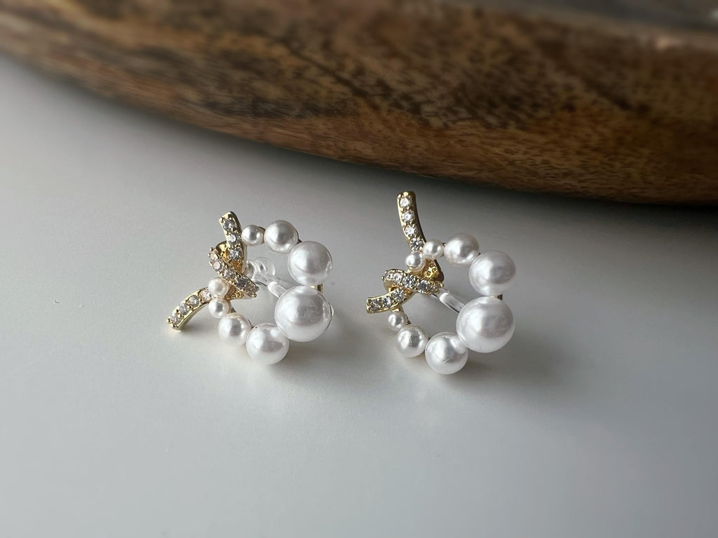 Boucles d’oreilles clip forme de couronne ornées perles blanches, strass scintillants. Finition dorée raffinée pour une touche sophistiquée.