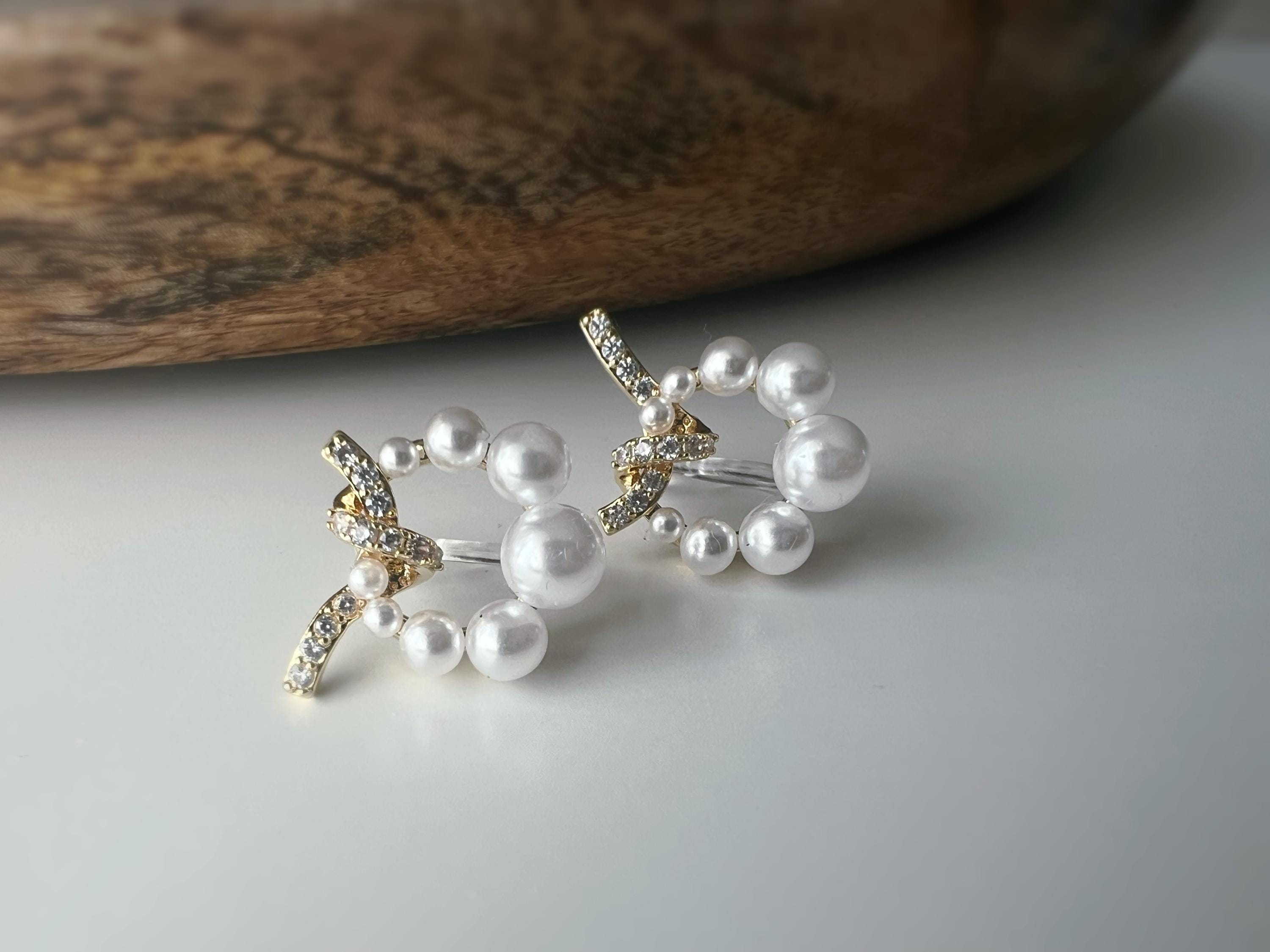 Boucles d’oreilles clip forme de couronne ornées perles blanches, strass scintillants. Finition dorée raffinée pour une touche sophistiquée.