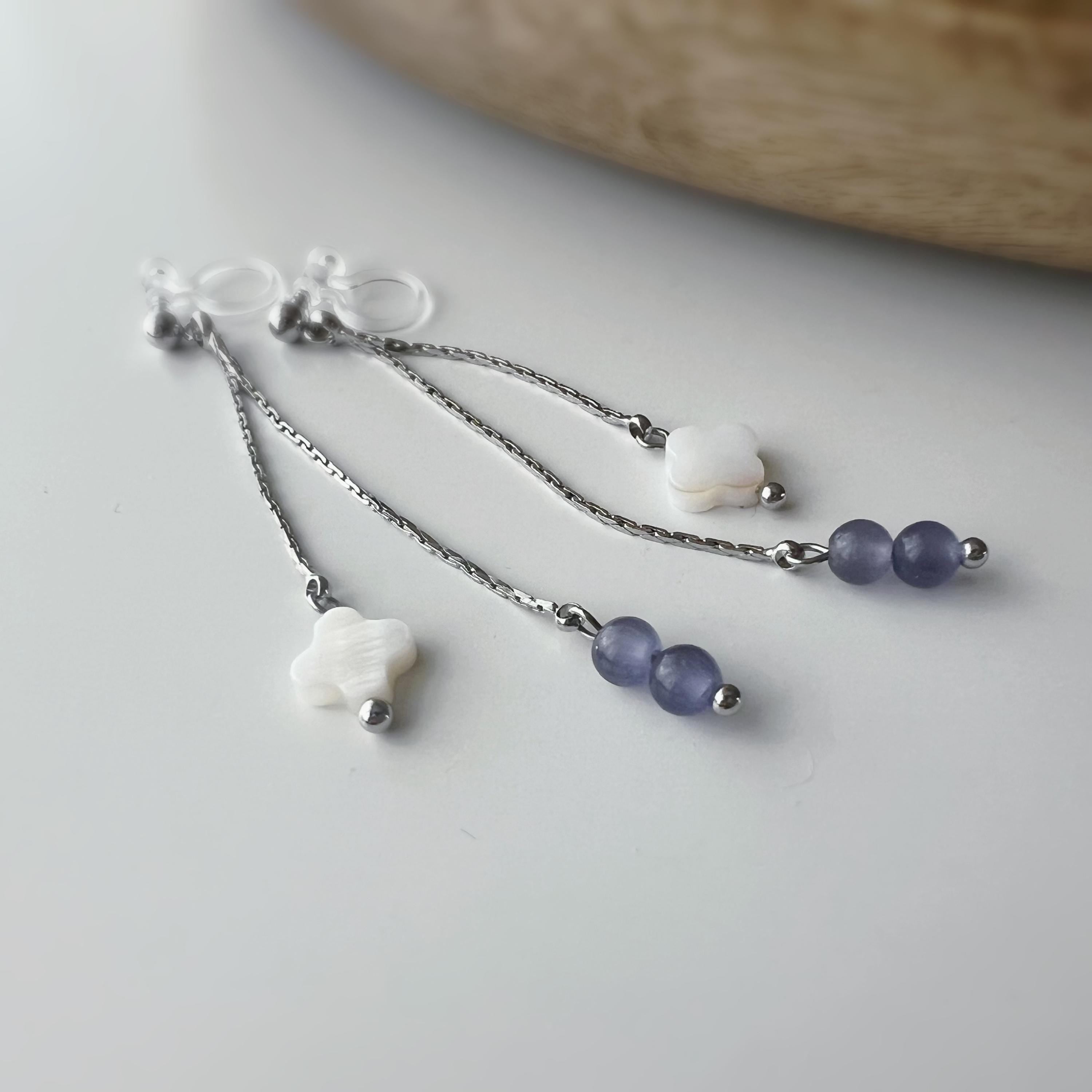 Boucles d'oreilles clip élégantes Chaîne argentée Perles violettes Fleur blanche en nacre Légères raffinées parfait pour style délicat chic.