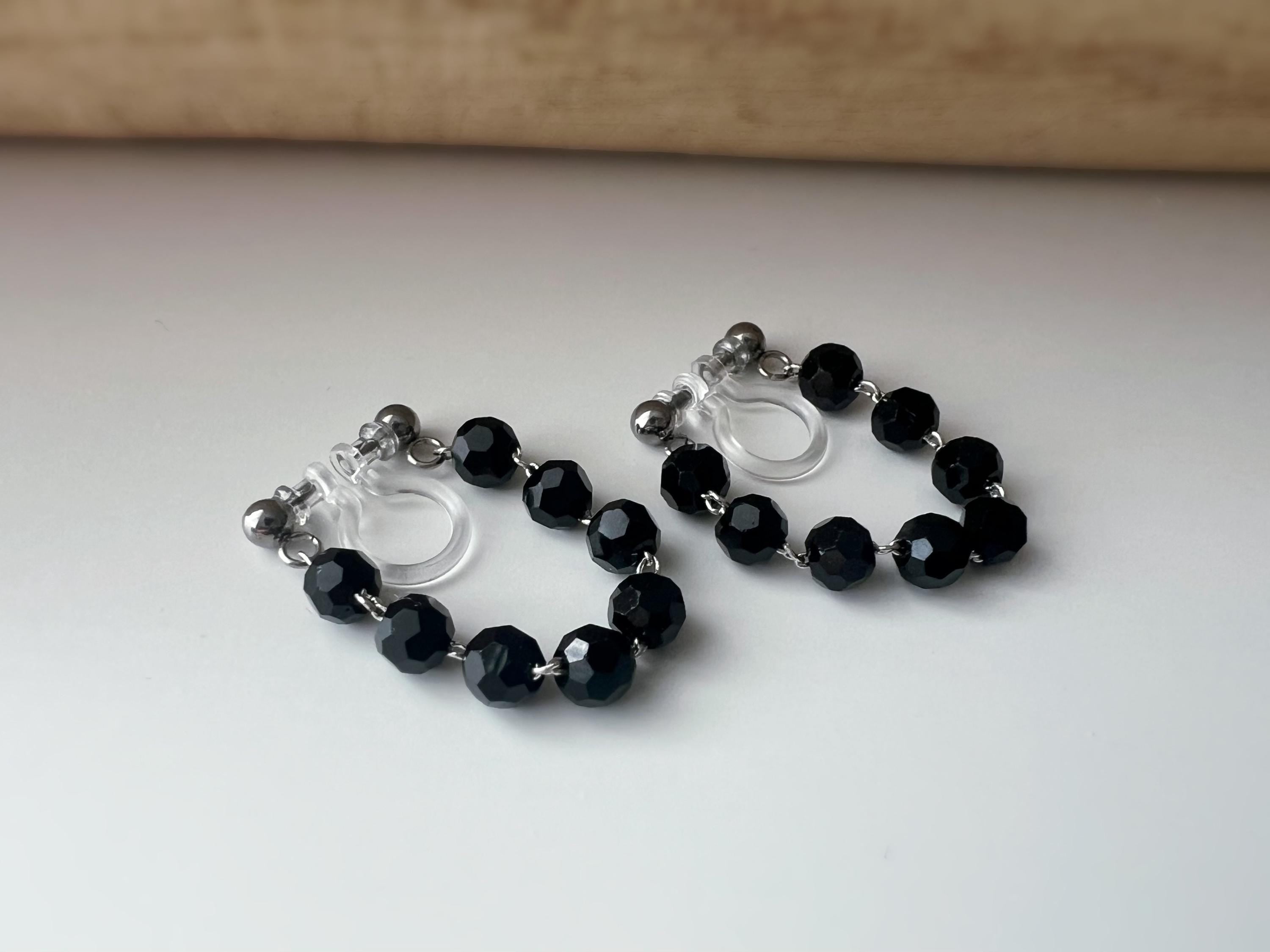 Boucles d'oreilles clips élégantes avec perles noires facettées en forme de cercle. Idéales pour un look raffiné et intemporel.