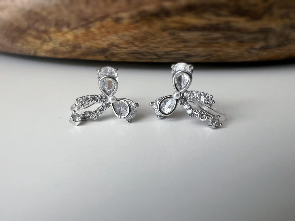 Clips d’oreilles papillon en strass, disponibles en doré et argenté. Design raffiné pour un look délicat, sans perçage.