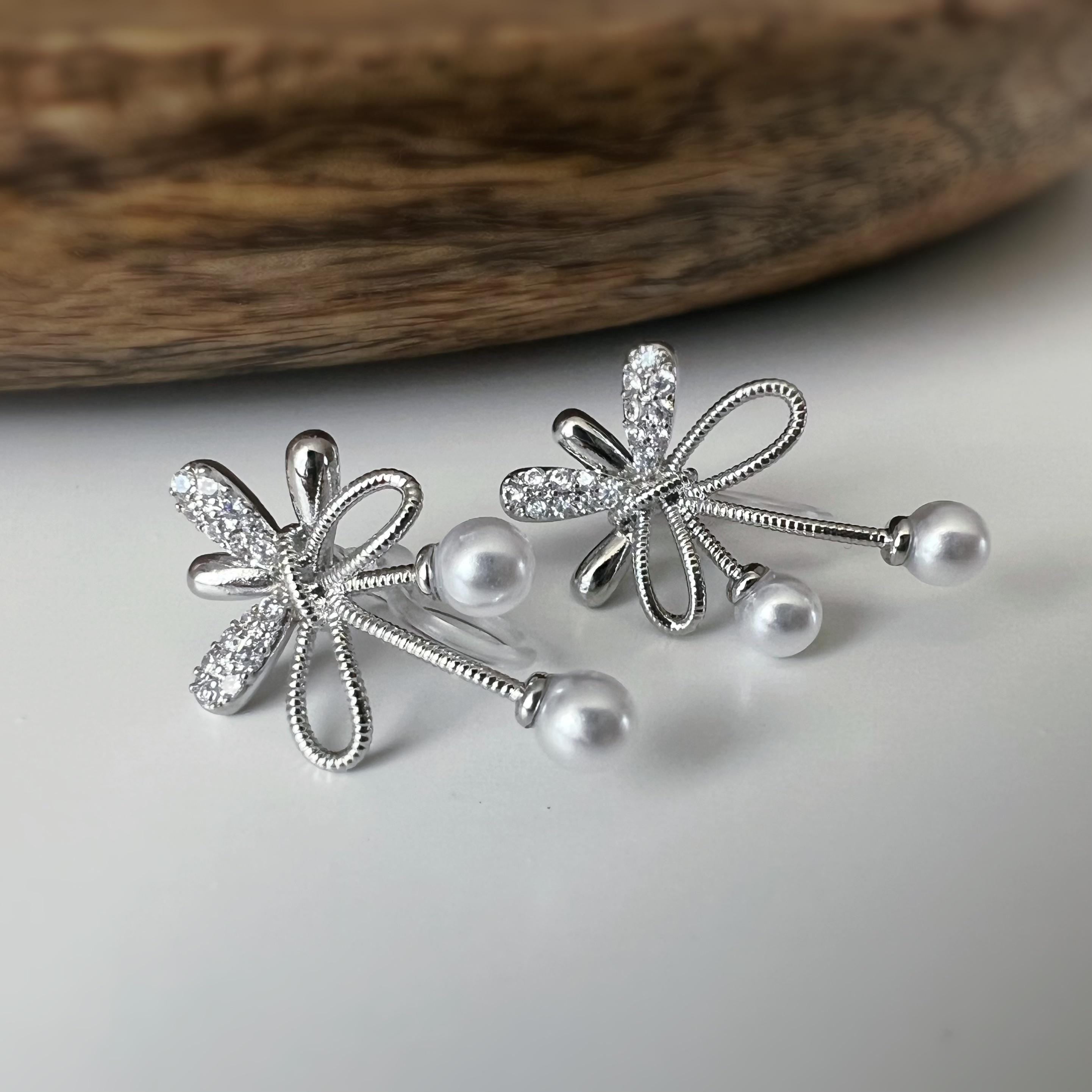 Boucles d’oreilles à clips fleurs strass, mini perles blanches couleur Or / Argent. Design raffiné pour un look délicat, sans perçage.