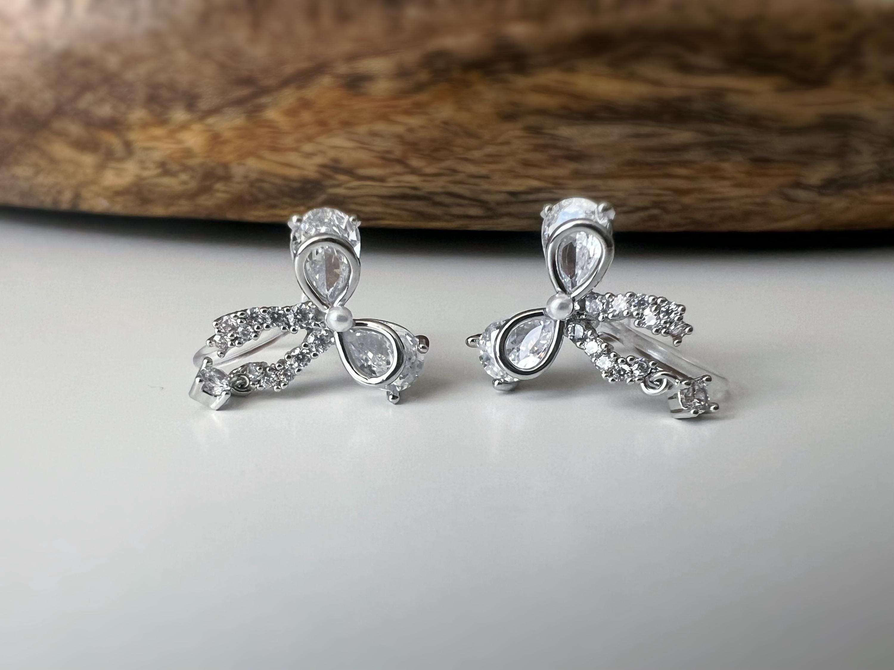 Clips d’oreilles papillon en strass, disponibles en doré et argenté. Design raffiné pour un look délicat, sans perçage.