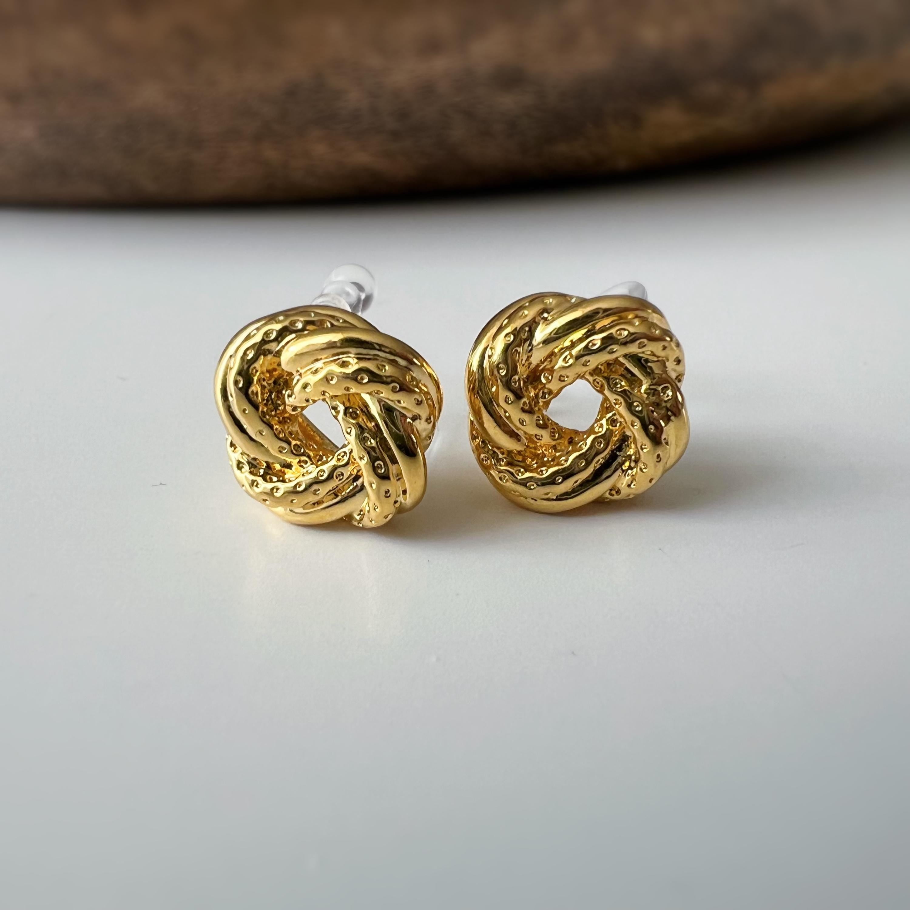 Clips d’oreilles nœud doré au design texturé. Élégantes et intemporelles, elles ajoutent une touche chic à toutes vos tenues.