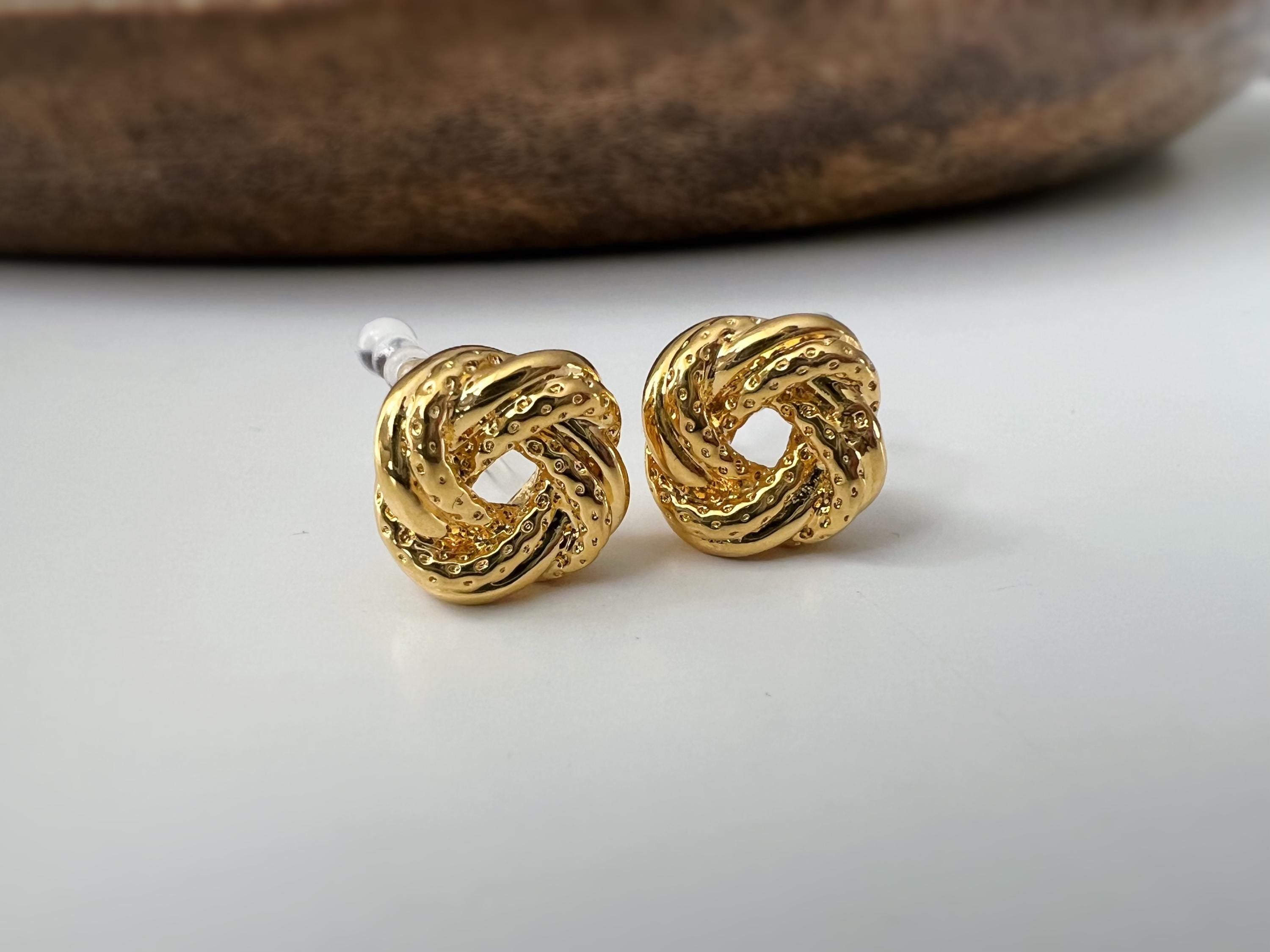 Clips d’oreilles nœud doré au design texturé. Élégantes et intemporelles, elles ajoutent une touche chic à toutes vos tenues.