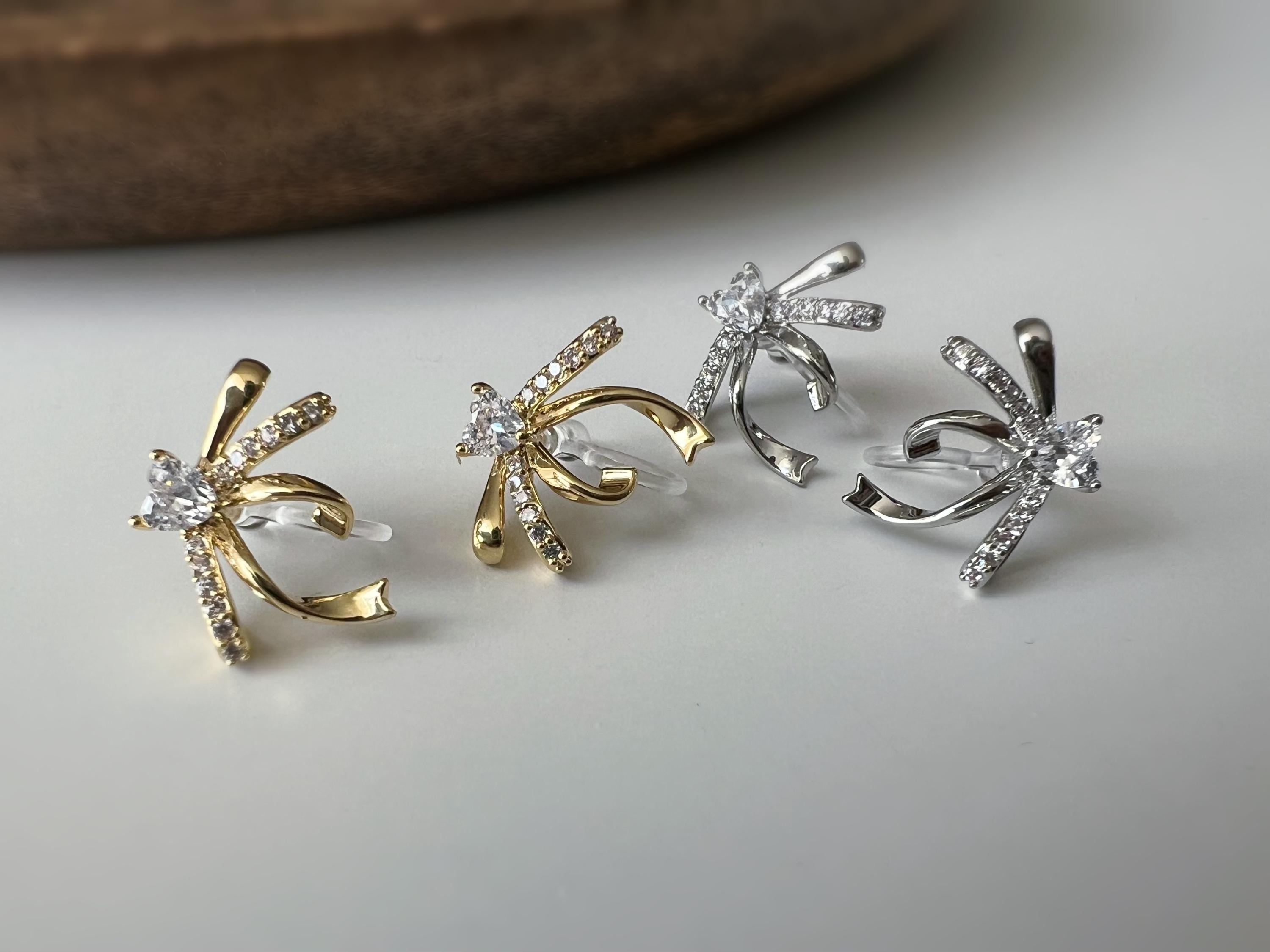 Clips d’oreilles élégants en forme de nœud scintillant Or / Argent sertis de strass étincelants. Bijou raffiné pour un style chic et féminin