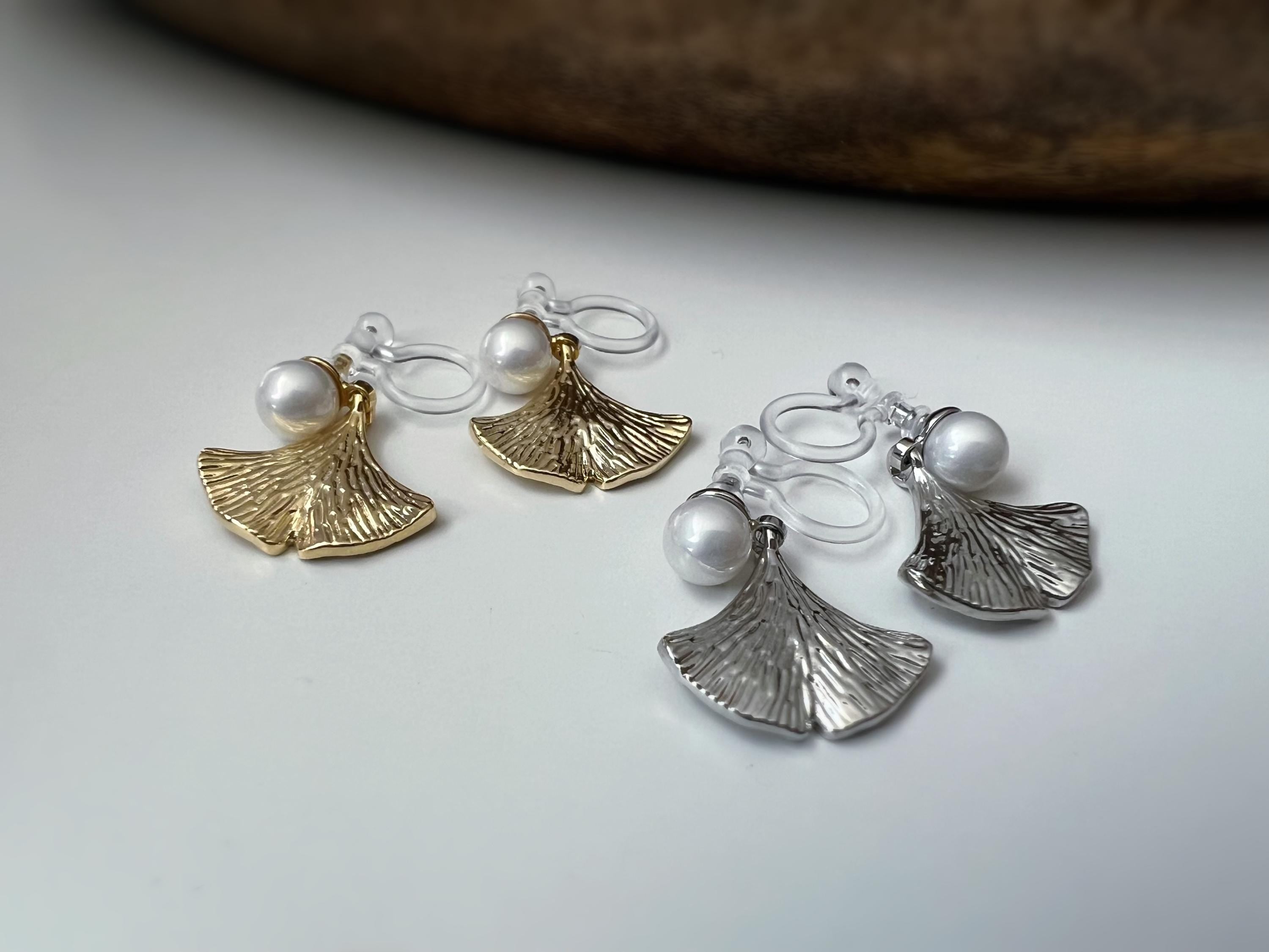 Clips d’oreilles élégants ornés d’une perle blanche et d’un pendentif feuille de ginkgo Or / Argent. Un bijou raffiné, chic et intemporel.