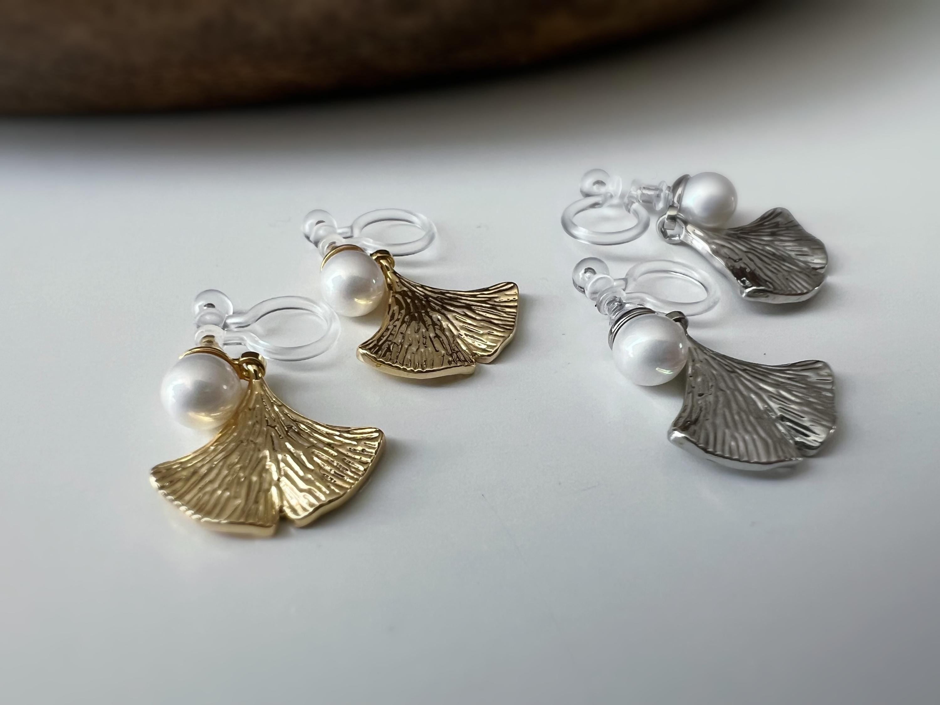 Clips d’oreilles élégants ornés d’une perle blanche et d’un pendentif feuille de ginkgo Or / Argent. Un bijou raffiné, chic et intemporel.