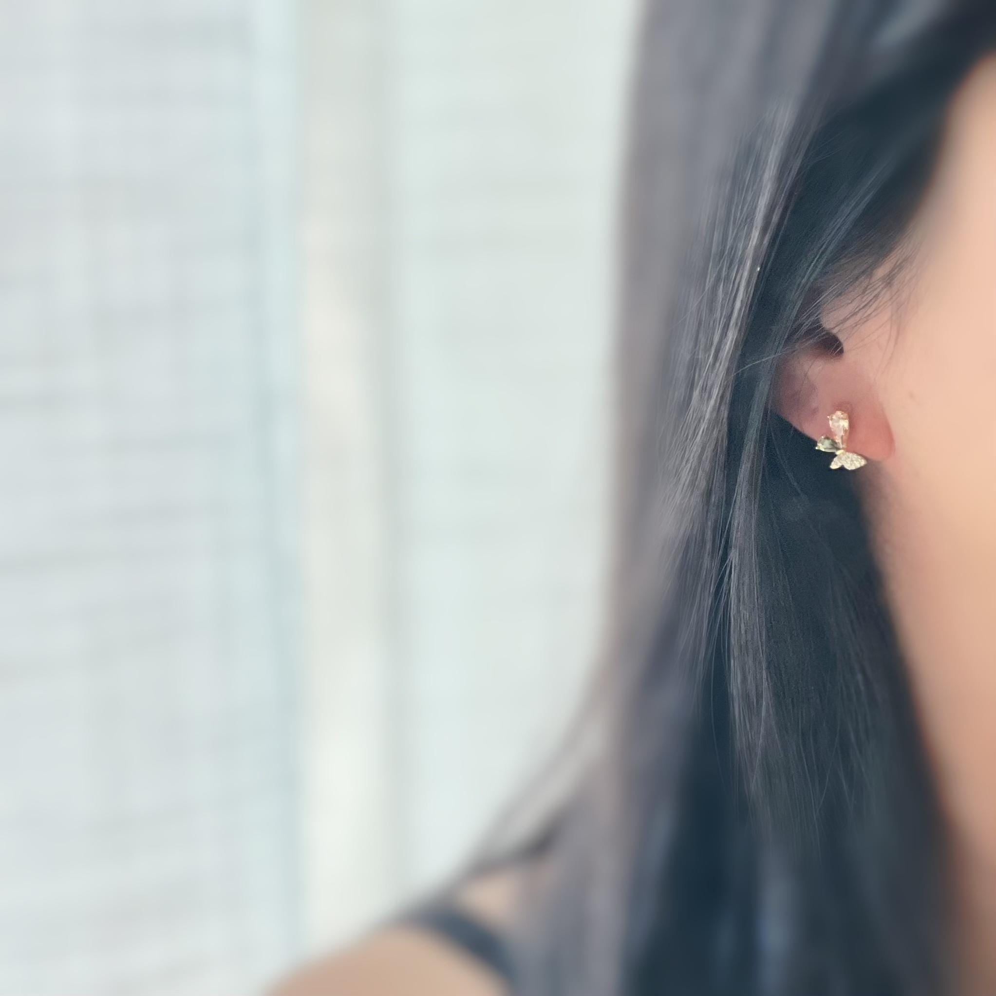 Clips d’oreilles papillon raffinés sertis de cristaux étincelants aux teintes champagne et vert olive. Un bijou délicat et lumineux.