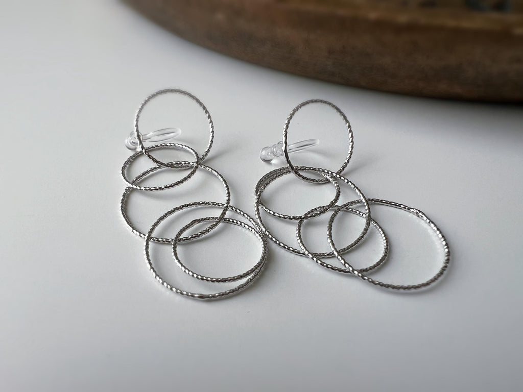 Boucles d'oreilles Clips, anneaux entrelacés argentés. Élégantes et légères, elles subliment vos looks avec une touche moderne et raffinée.