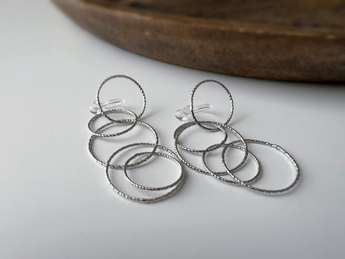 Boucles d'oreilles Clips, anneaux entrelacés argentés. Élégantes et légères, elles subliment vos looks avec une touche moderne et raffinée.