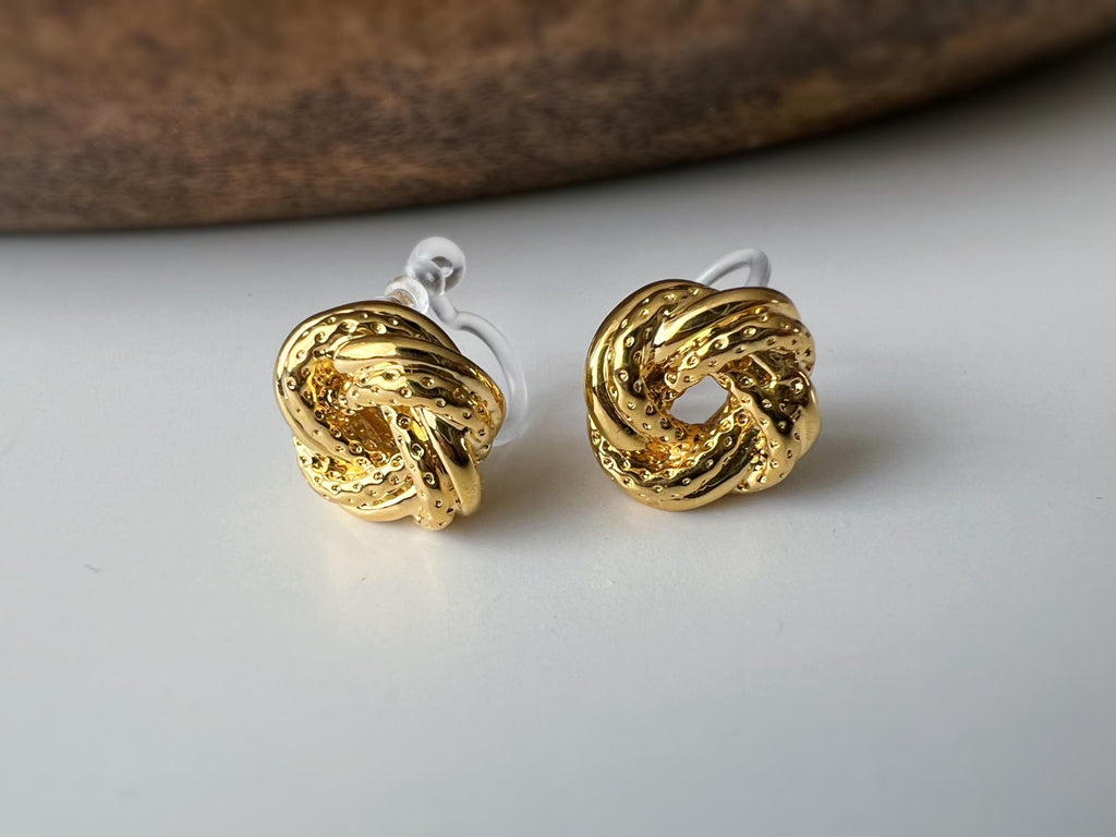 Clips d’oreilles nœud doré au design texturé. Élégantes et intemporelles, elles ajoutent une touche chic à toutes vos tenues.
