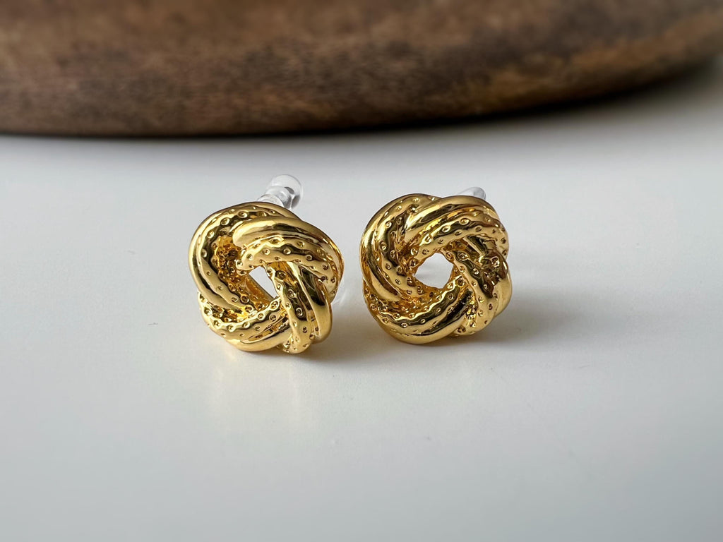 Clips d’oreilles nœud doré au design texturé. Élégantes et intemporelles, elles ajoutent une touche chic à toutes vos tenues.
