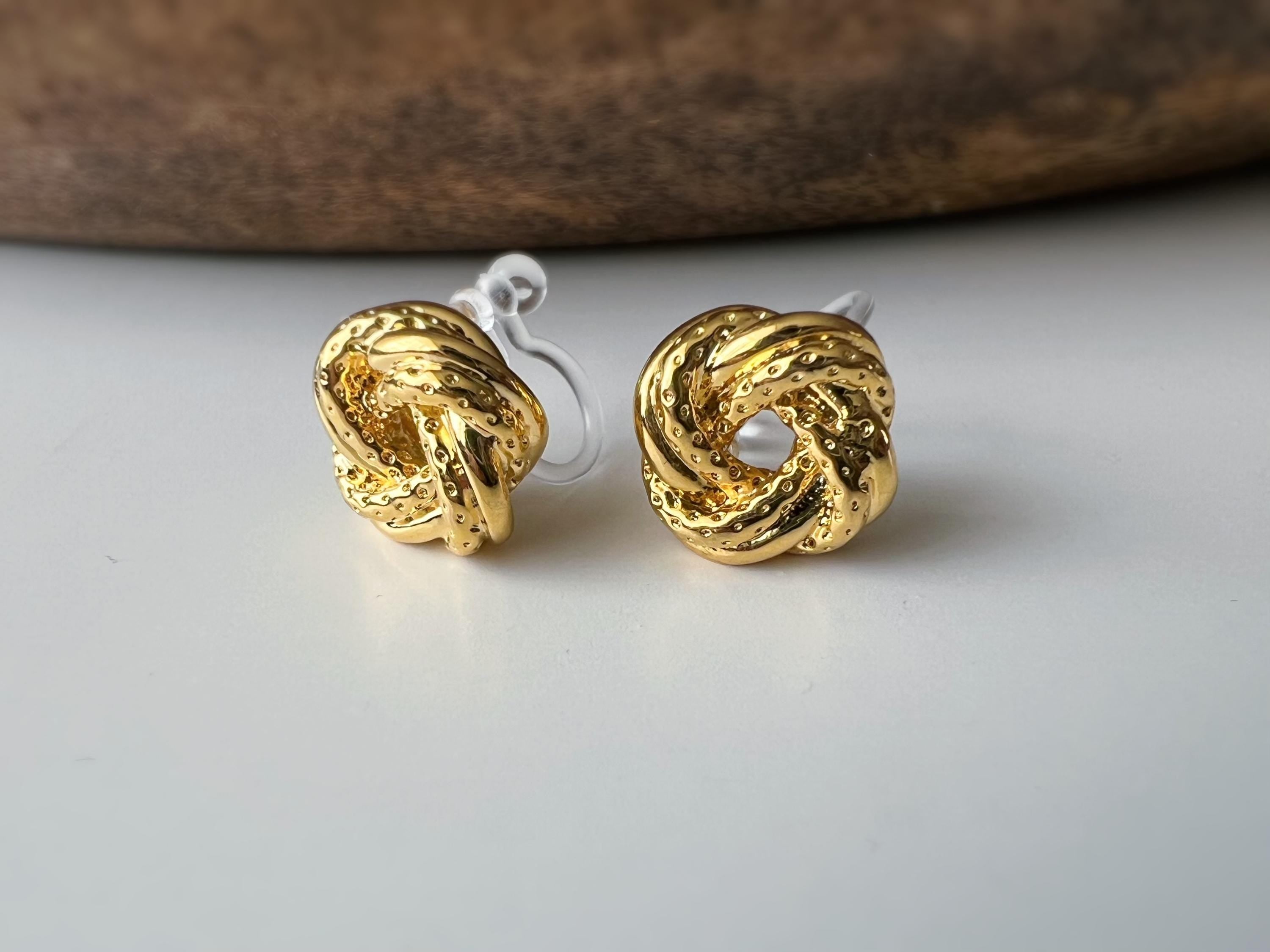 Clips d’oreilles nœud doré au design texturé. Élégantes et intemporelles, elles ajoutent une touche chic à toutes vos tenues.