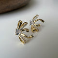 Clips d’oreilles élégants en forme de nœud scintillant Or / Argent sertis de strass étincelants. Bijou raffiné pour un style chic et féminin