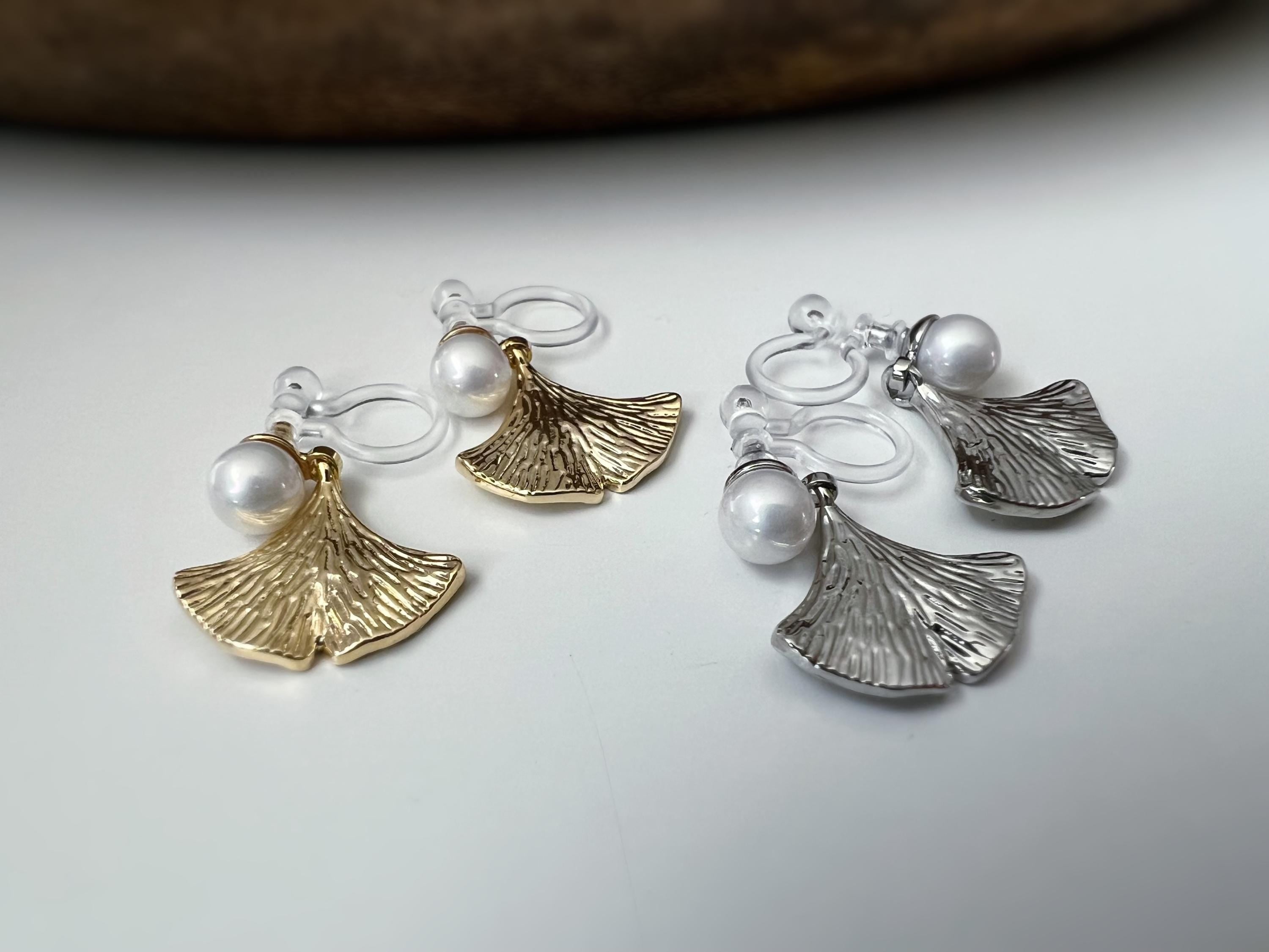 Clips d’oreilles élégants ornés d’une perle blanche et d’un pendentif feuille de ginkgo Or / Argent. Un bijou raffiné, chic et intemporel.
