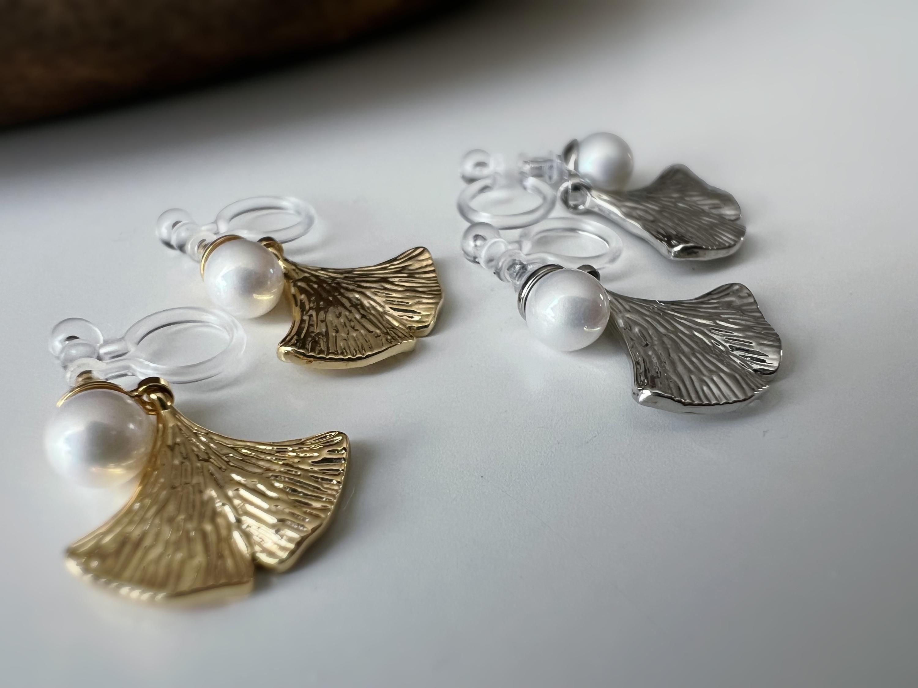 Clips d’oreilles élégants ornés d’une perle blanche et d’un pendentif feuille de ginkgo Or / Argent. Un bijou raffiné, chic et intemporel.
