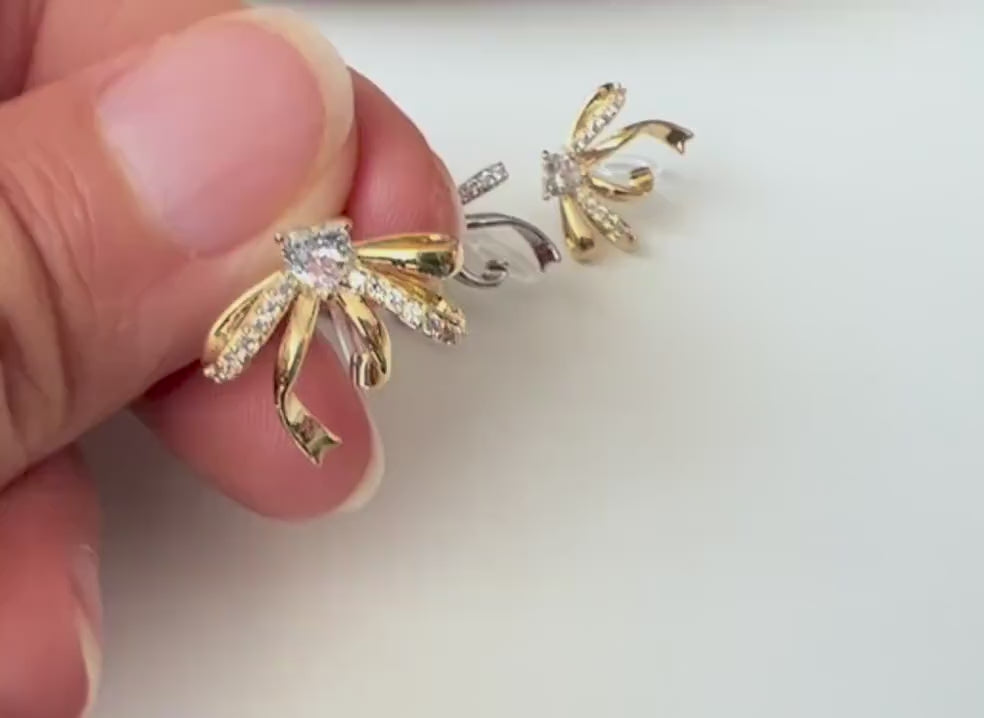Clips d’oreilles élégants en forme de nœud scintillant Or / Argent sertis de strass étincelants. Bijou raffiné pour un style chic et féminin
